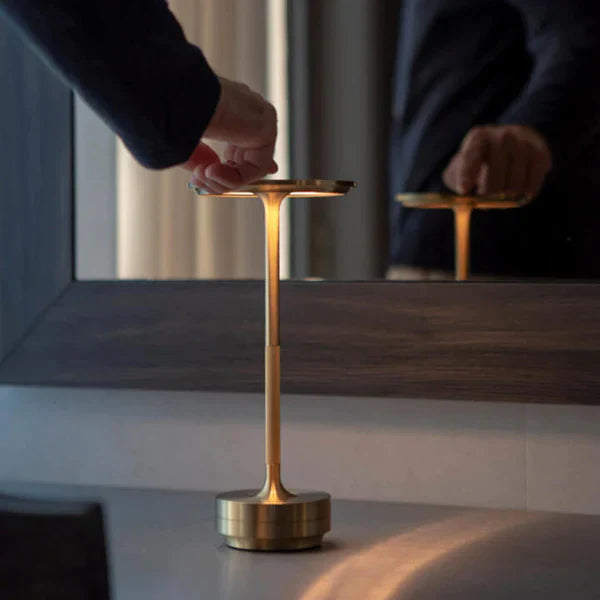 Gold cordless LED table lamp being dimmed by touch on a hallway console