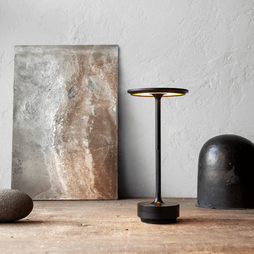 Black cordless table lamp styled on a wooden shelf with stone decor