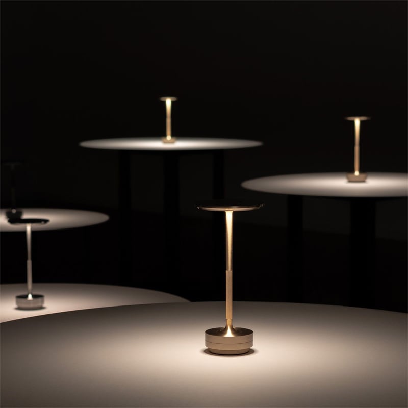 Gold and silver cordless table lamps lit across restaurant tables at night