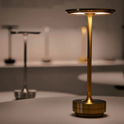 Close-up of the gold cordless lamp lit, restaurant tables behind