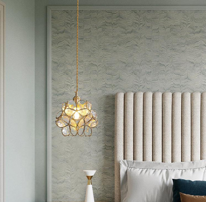 Glass Petal Pendant Light hanging beside an upholstered bed headboard