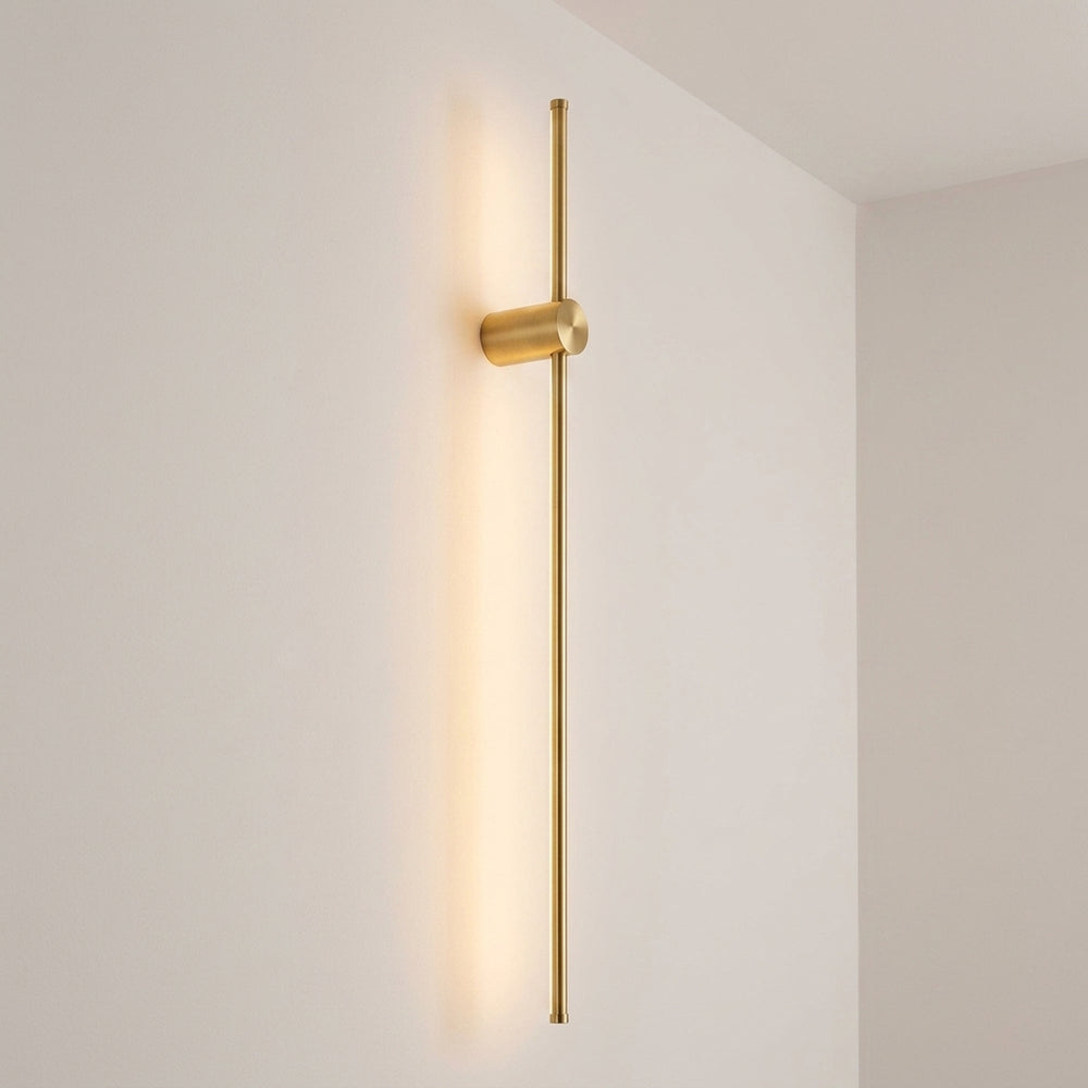 Contemporary Linear Wall Light in brushed gold, wall mounted with the fixing about a fifth of the way down the bar