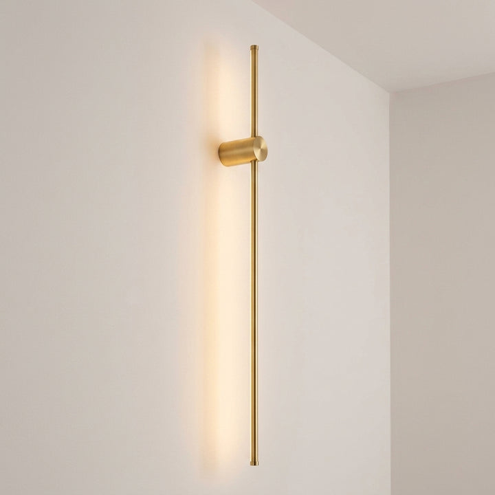 Contemporary Linear Wall Light in brushed gold, wall mounted with the fixing about a fifth of the way down the bar